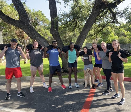 A Chalk Training group carrying sandbags during an outdoor conditioning session in Westlake, Austin